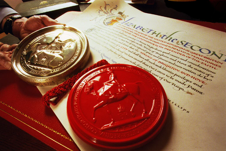 A man holds a solid silver matrix next to a red seal on a piece of calligraphed parchment.
