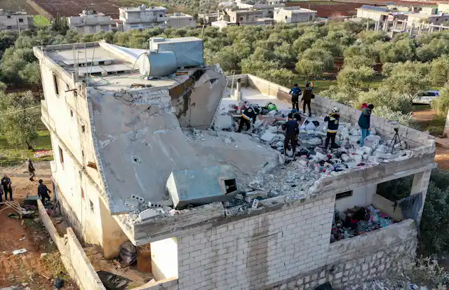 People inspect a destroyed house.