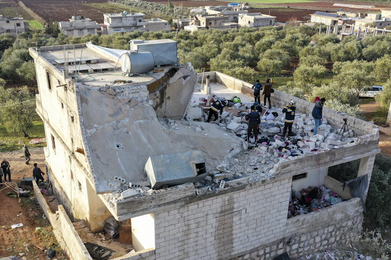 People inspect a destroyed house.