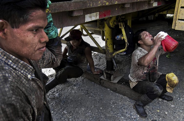 Banana plantation workers in Panama find shade under a vehicle during a break.