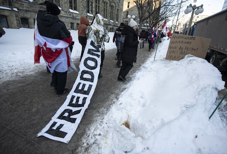 A person walks on a sidewalk as a long banner that reads 'freedom' trails behind them.