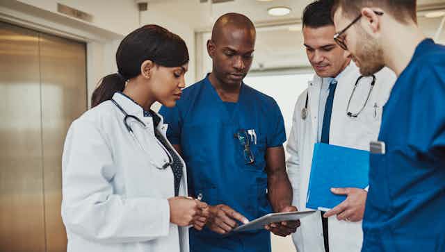 A group of doctor seen discussing a chart.