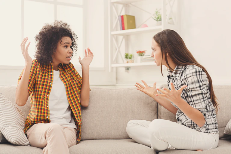 2 women arguing as they sit on a couch
