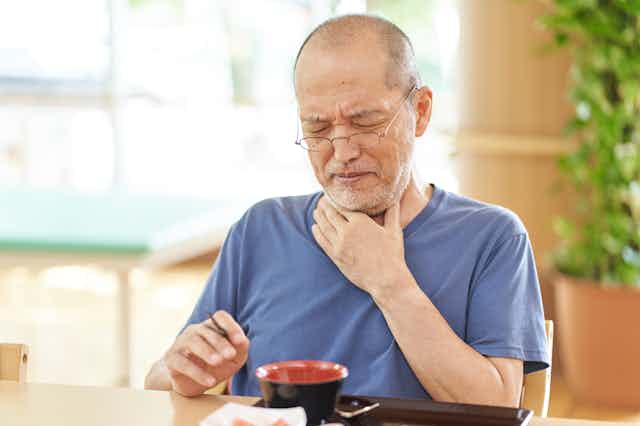 An older man struggles to swallow