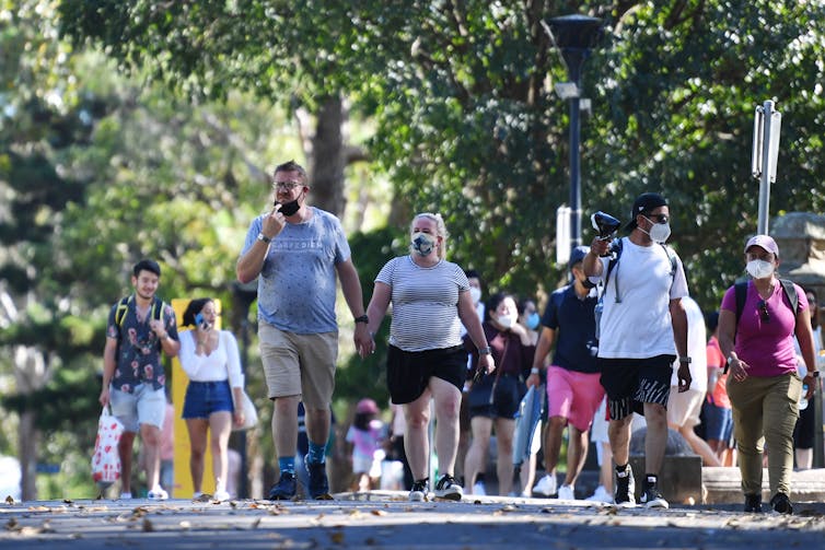 people walk in park. some wear masks