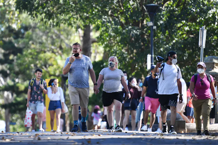 people walk in park. some wear masks
