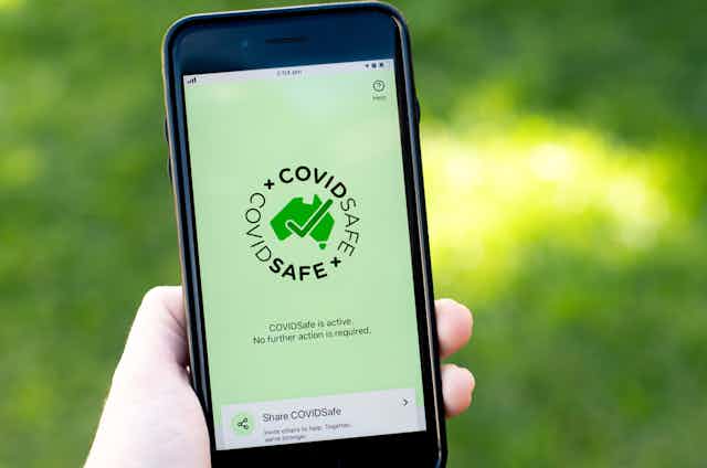 Person holding smartphone with CovidSafe app on screen
