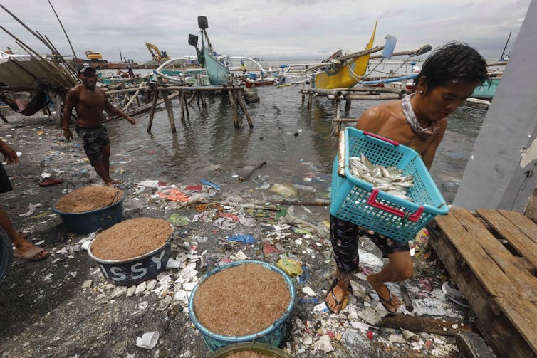 Fishermen bring their catch ashore a polluted bank