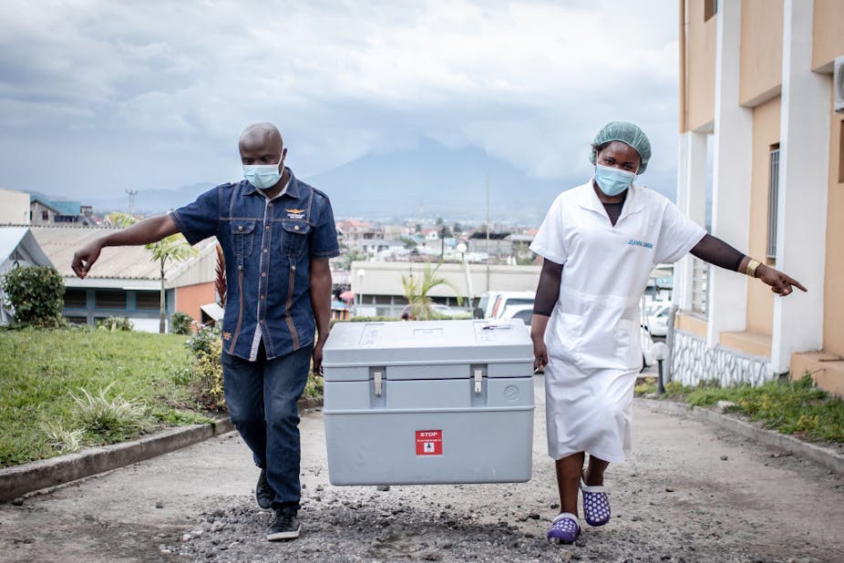 Man and woman carrying a box with vaccines.
