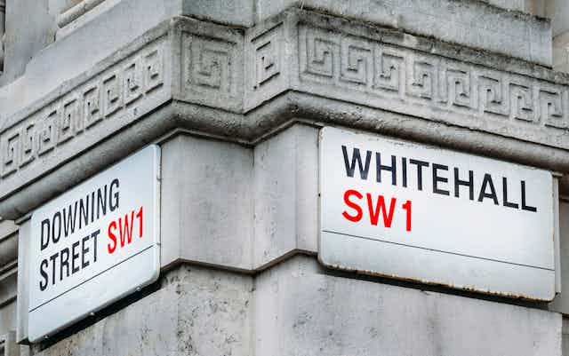 Street signs at the corner of Downing Street and Whitehall, on the side of a stone government building
