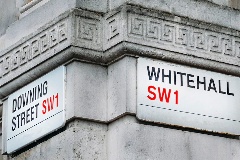 Street signs at the corner of Downing Street and Whitehall, on the side of a stone government building