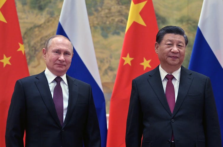 Vladimir Putin and Xi Jinping posing in front of flags