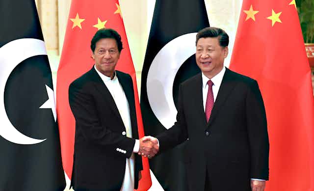 Pakistan prime minister Imran Khan shakes hands with Chinese president Xi Jinping in front of Chinese and Pakistani flags