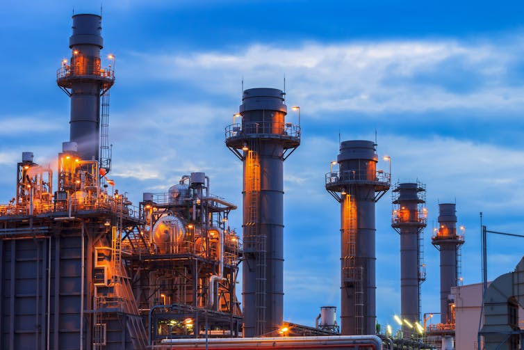 Five chimneys tower above an industrial facility webbed with pipes.