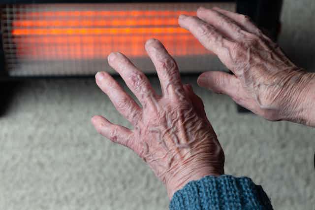 Elderly hands in front of radiator