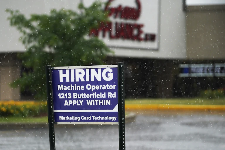 A blue and white 'hiring' sign outside an appliance store..