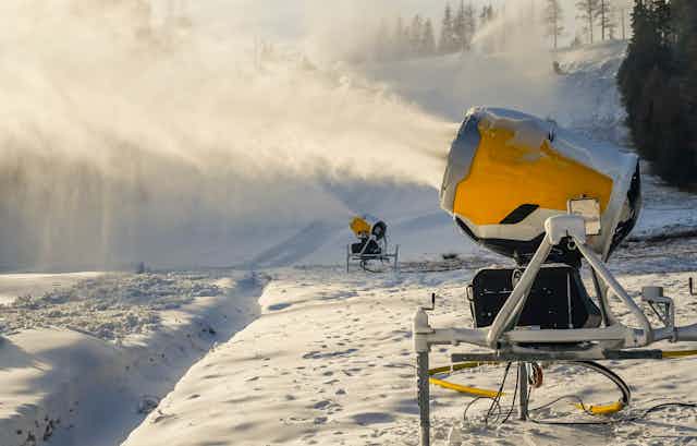 Two snowguns blowing snow onto a mountainside.