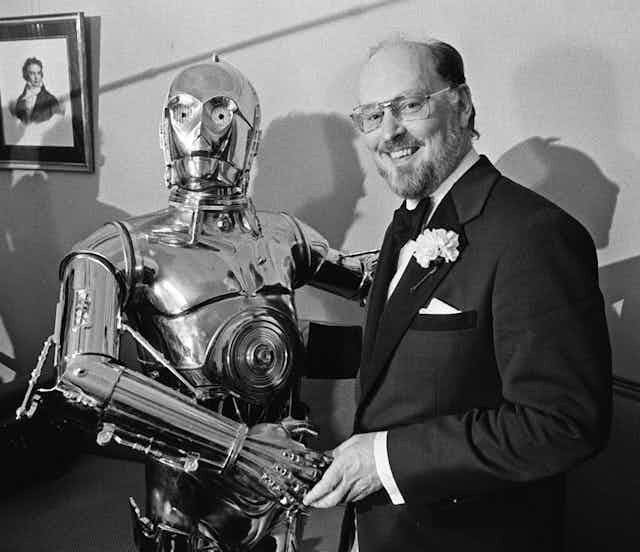 John Williams, right, shakes hands with Star Wars character C-3PO 