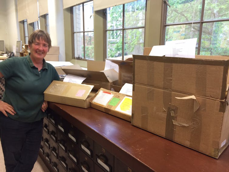 woman smiling at camera next to boxes on bench