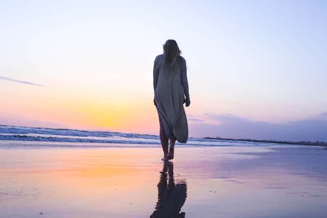 woman walking on sunset beach