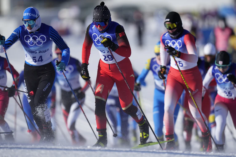 Three women cross-country skiers in the foreground with other competitors behind them