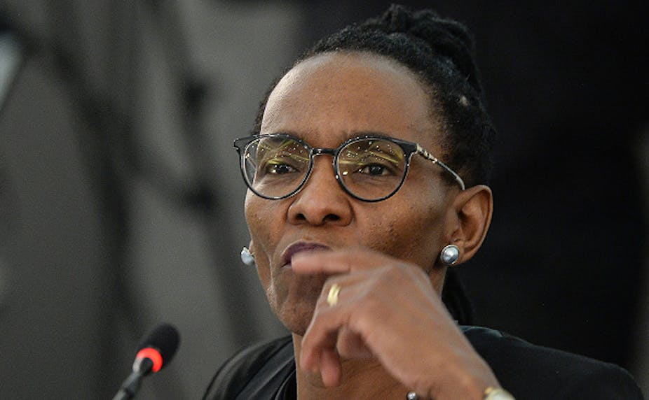 A black woman wearing reading glasses stares attentively