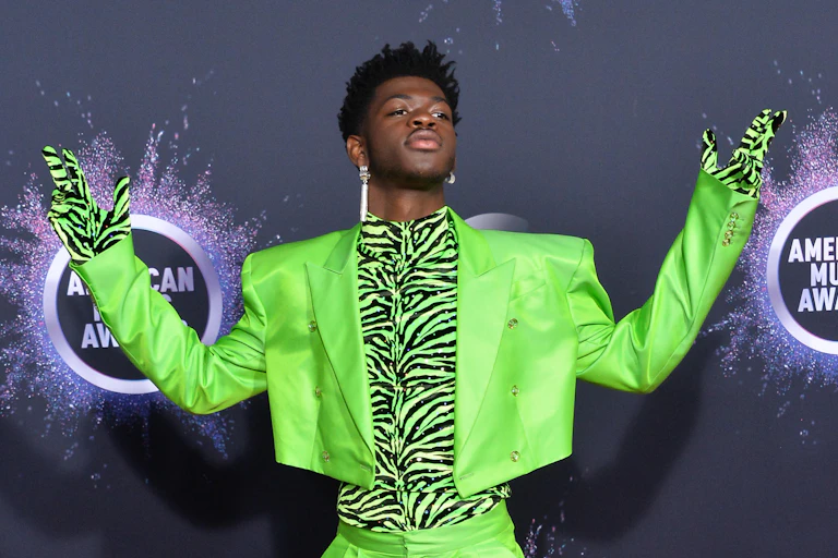 Lil Bas in green suit with green tiger print top and gloves.