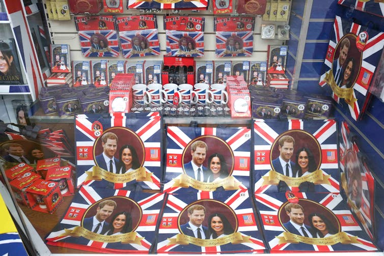 A shop window display filled with bags, mugs and flags showing Harry and Meghan's portrait over the Union Jack.