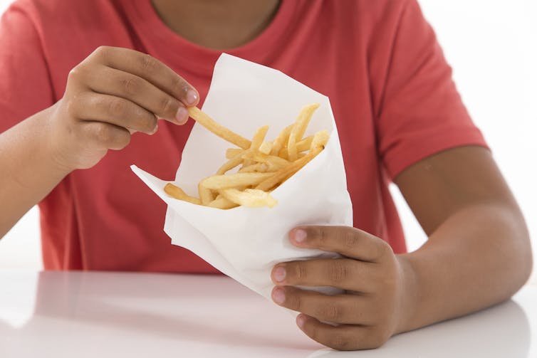 Cropped image of a boy eating french fries