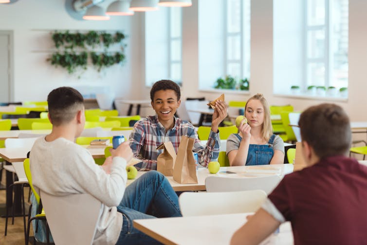 A group of teens eating lunch in a school cafeteria
