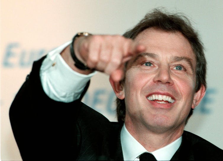 Young Tony Blair smiles and points during a press conference