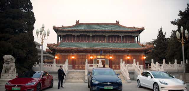 Three Teslas are parked outside a traditional Chinese building 