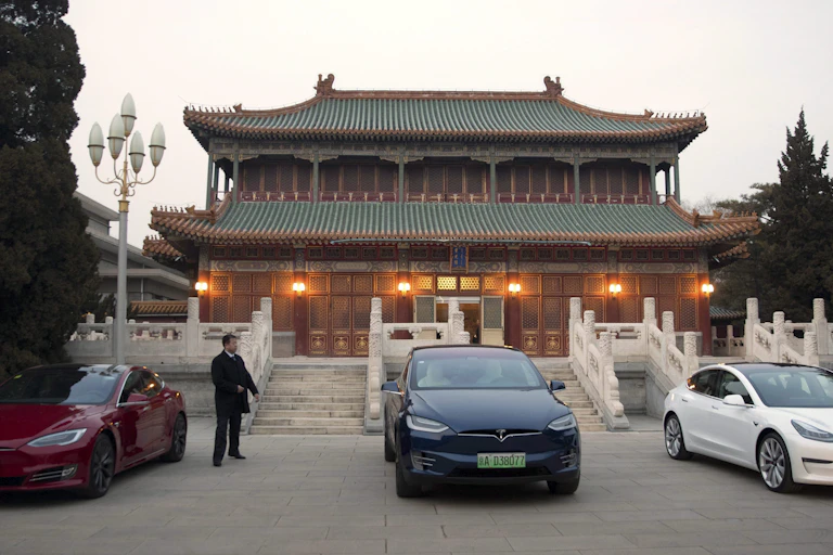Three Teslas are parked outside a traditional Chinese building