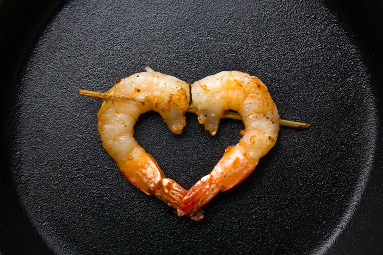 dos gambas a la plancha ensartadas en un palillo haciendo un corazón