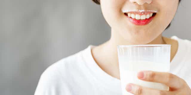 Asian girl smiles while holding a glass of milk.