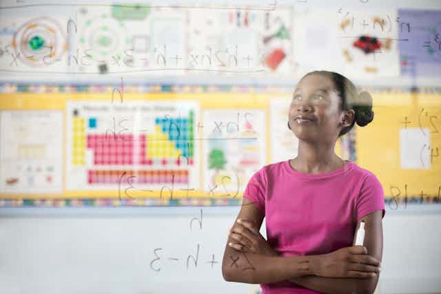 A girl looks at formulas written on a transparent 