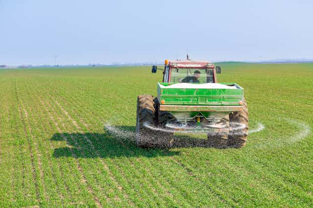 Un tractor fertilizando un campo agrícola.