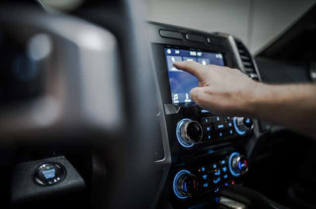 Una mano manipula los botones de una radio de coche.