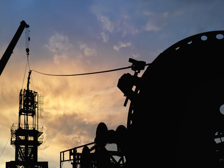 Silhouette of an oil and gas rig at sunset.