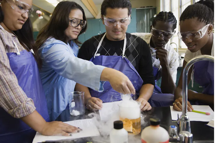 A group of diverse science students conduct an experiment on a lab bench.