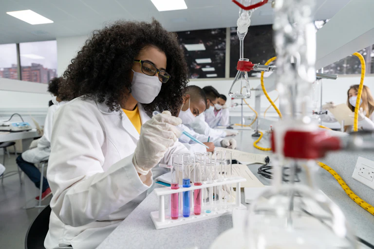 A Black woman works with test tubes in a science lab.