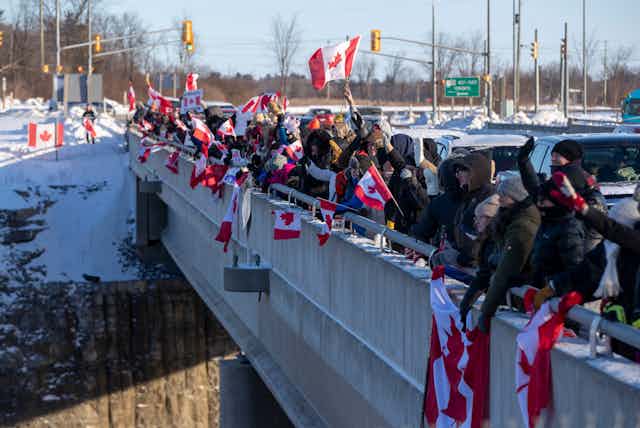 People wave Canada flags on an overpass