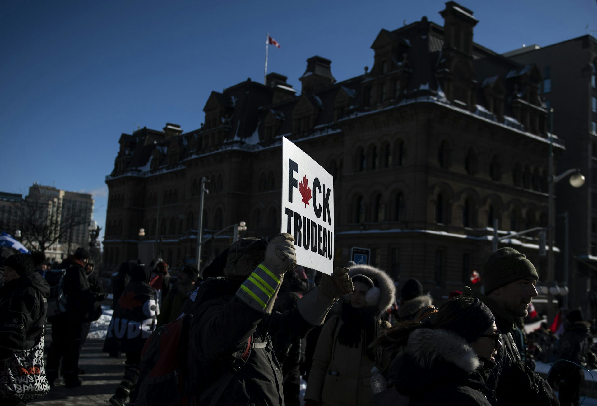 A protester holds a sign that says fuck trudeau