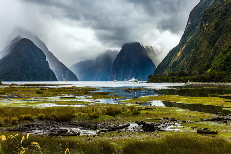 Natural landscape, with mounatins and tourist boats in a fiord, Fiordland National Park in New Zealand.
