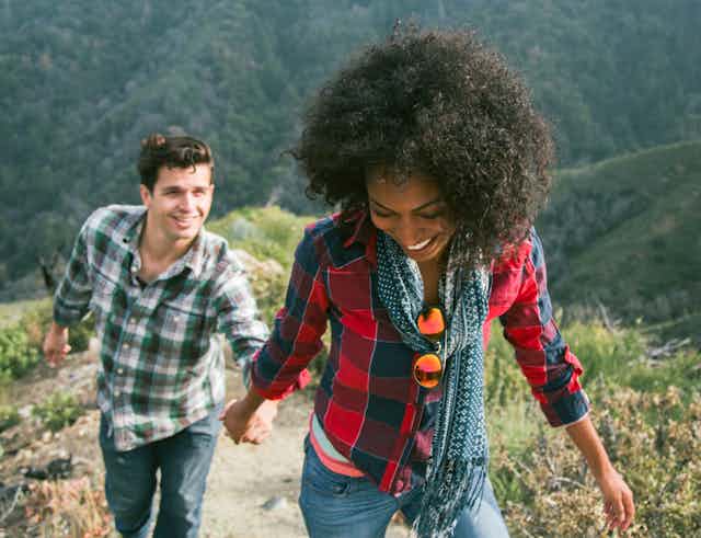 woman leads man up a mountain trail