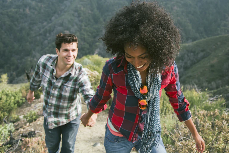 woman leads man up a mountain trail