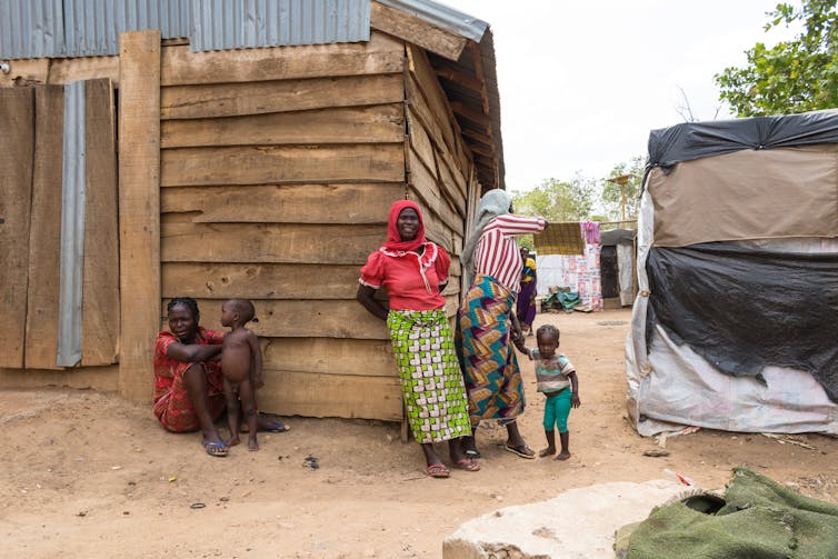 Women outside a wooden house in Abuja.
