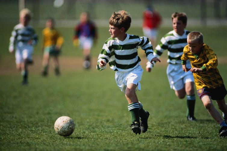 Children play soccer on a grassy field.