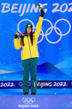 Jakara Anthony poses with one arm in the arm and gold medal in the other hand