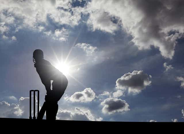 Cricketer silhouetted against sun